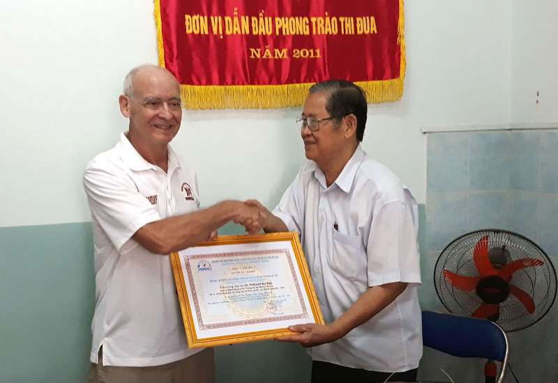 Thêm 417 bệnh nhân được lắp tay chân giả Ông Huỳnh Văn Cam - Chủ tịch Hội trao thư cảm ơn đến Giáo sư, Tiến sĩ Richard Kerr Kunz. Ảnh: N. Diệu