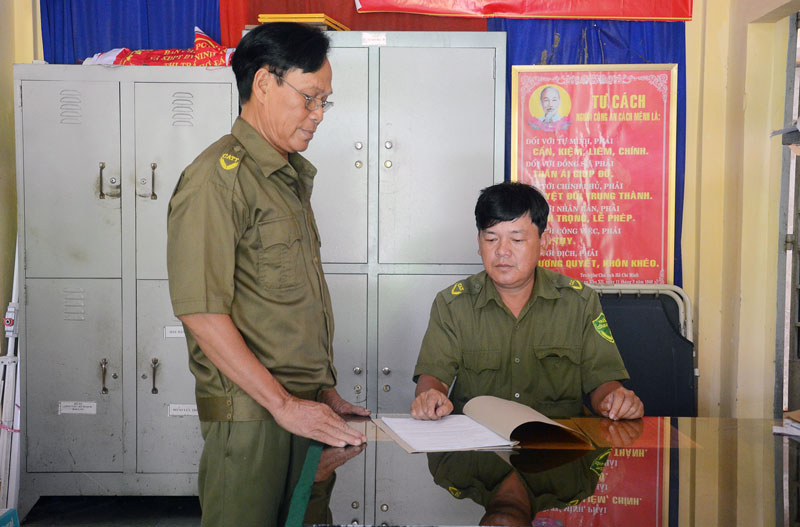 Anh Huỳnh Trí Nghĩa (ngồi) đang trao đổi công việc với công an viên.