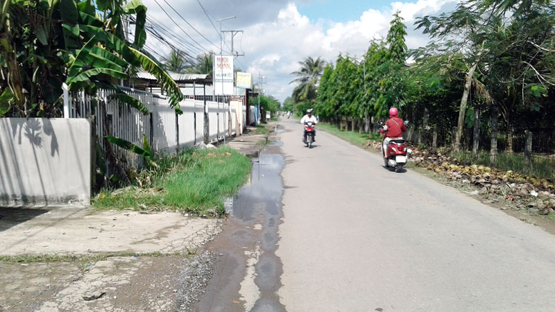 Một đoạn huyện lộ 173, xã Tam Phước, huyện Châu Thành bị đọng nước từ hồ nước thải tràn ra. Ảnh: PV