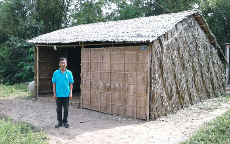 Ông Nguyễn Văn Dũng bên mái nhà lá do bà con chòm xóm dựng lên. 