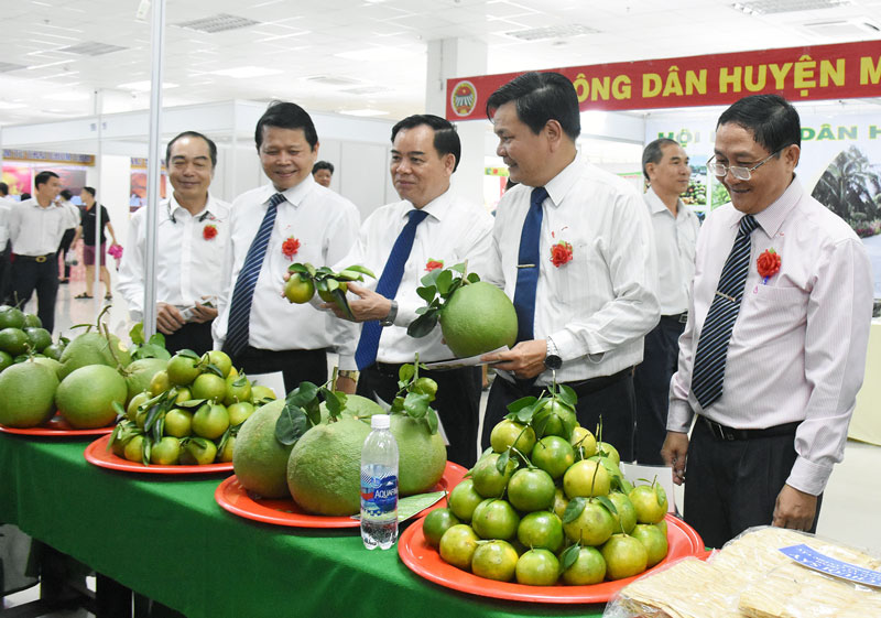 Phó bí thư Tỉnh ủy Trần Ngọc Tam và Phó chủ tịch UBND tỉnh Nguyễn Hữu Lập tham quan gian hàng sản phẩm OCOP của huyện Mỏ Cày Bắc.  Ảnh: C. Trúc