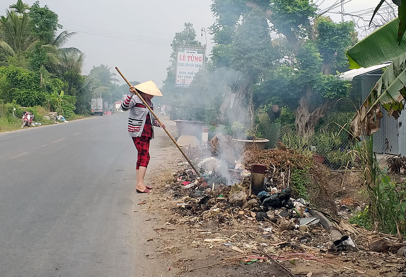 Người dân đốt rác ven đường quốc lộ 57 đoạn qua huyện Chợ Lách. Ảnh: T.Đồng