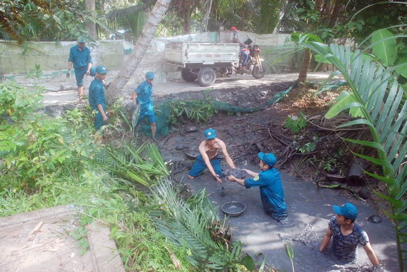 Thắt chặt đoàn kết quân dân trong xây dựng nông thôn mới Dân quân tự vệ huyện Mỏ Cày Bắc giúp xã Tân Thanh Tây đắp triên lộ liên ấp.