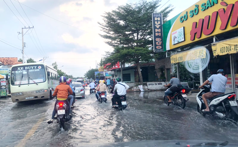 Triều cường cao làm nhiều đoạn đường trên quốc lộ 60, đoạn thị trấn Mỏ Cày Nam bị ngập nước, người dân lưu thông khó khăn. (ảnh chụp lúc 5 giờ ngày 29-9-2019 - N. Hùng)