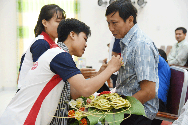 Chiến sĩ tình nguyện Trường Cao đẳng Bến Tre cài hoa tri ân gia đình nuôi quân tại chương trình họp mặt.