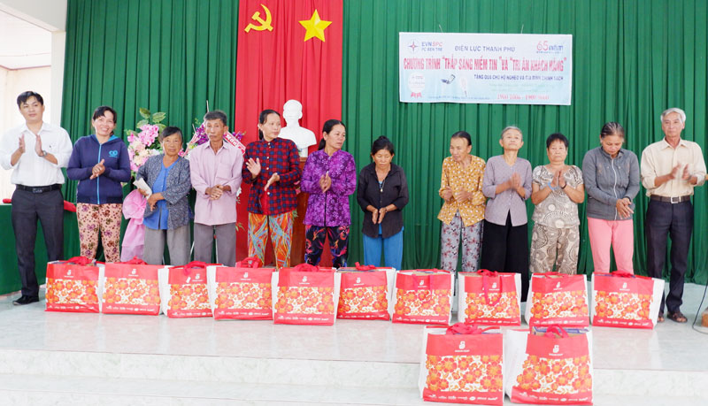 Đại diện Điện lực Thạnh Phú (bìa trái) trao quà cho các hộ nghèo, gia đình chính sách.
