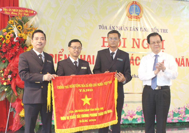 Phó Chánh án TAND tối cao Lê Hồng Quang (bìa phải) trao Cờ thi đua của Chính phủ cho đại diện lãnh đạo TAND tỉnh