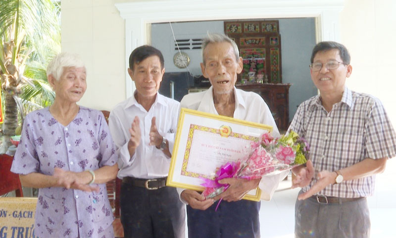 Phó Bí thư Thường trực Huyện ủy Phạm Văn Bé Năm trao quyết định và hoa chúc mừng cho đảng viên Nguyễn Tấn Ngân