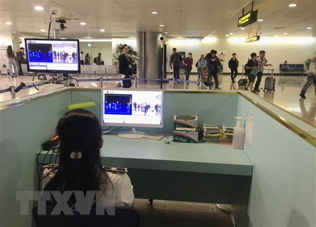 Nhân viên sân bay Tân Sơn Nhất kiểm tra màn hình hiển thị máy quét thân nhiệt đối với hành khách quốc tế đến Việt Nam. Ảnh: Đinh Hằng/TTXVN