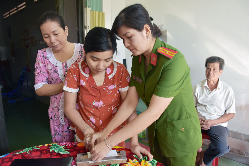 Thiếu tá Lê Thị Kiều Trang làm giấy chứng minh nhân dân cho người khuyết tật ở thị trấn Mỏ Cày.