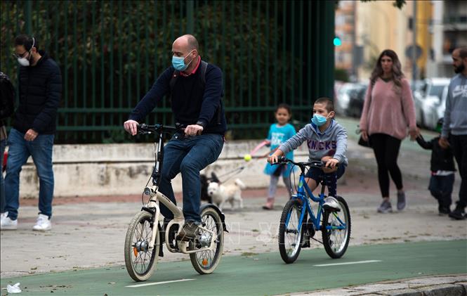 Người dân đeo khẩu trang đạp xe tại Seville, Tây Ban Nha, ngày 26-4-2020. Ảnh: AFP/TTXVN