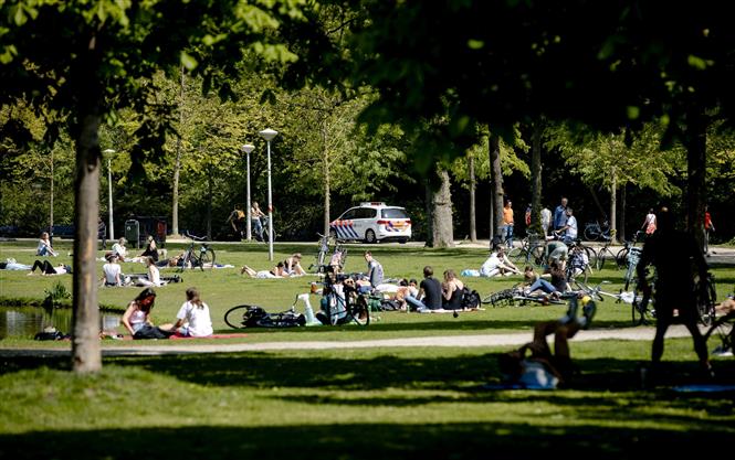  Người dân sưởi nắng tại một công viên ở Amsterdam, Hà Lan ngày 27-4-2020. Ảnh: AFP/TTXVN