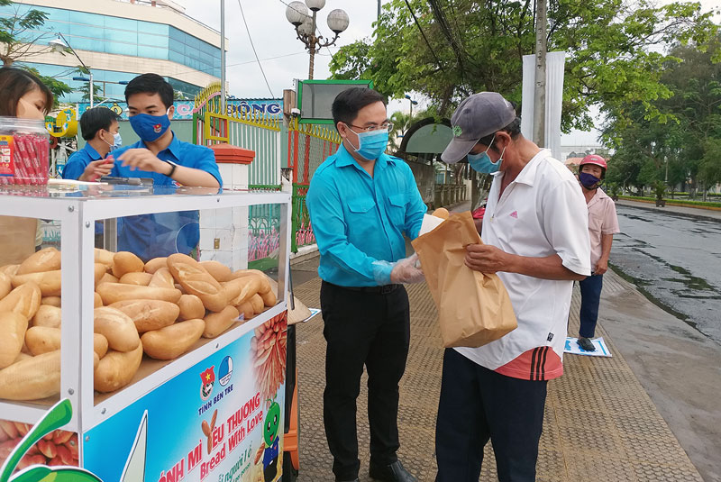 Anh Phan Thanh Trẻ cùng cán bộ đoàn tặng bánh mì và nhu yếu phẩm cho người dân tại hoạt động Tủ bánh mì yêu thương. Ảnh: Thanh Đồng