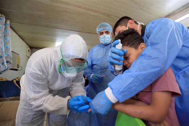 Nhân viên y tế lấy mẫu xét nghiệm COVID-19 cho một em nhỏ tại Baghdad, Iraq ngày 21-5-2020. Ảnh: THX/TTXVN