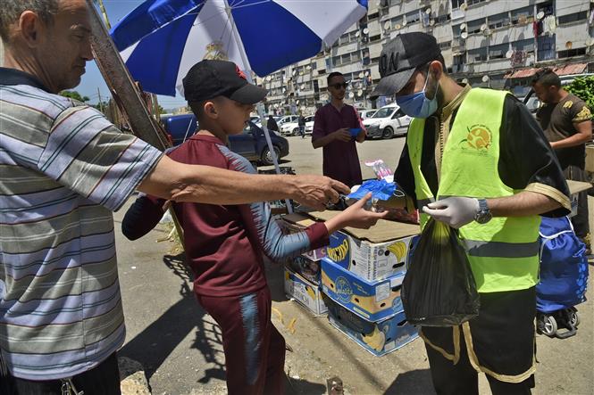 Phân phát khẩu trang miễn phí cho người dân phòng lây nhiễm COVID-19 tại thủ đô Algiers, Algeria. Ảnh: AFP/TTXVN