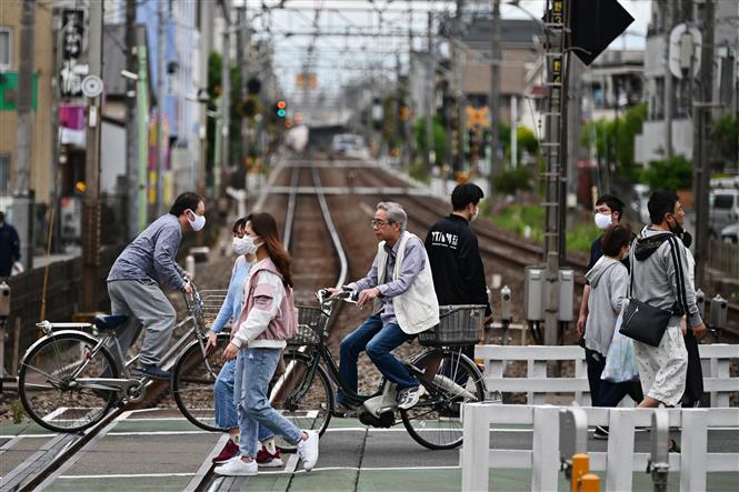  Người dân đi xe đạp qua đường ray tàu hỏa tại Tokyo, Nhật Bản, ngày 4-5-2020. Ảnh: AFP/ TTXVN