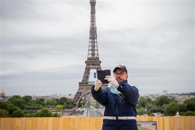 Khách du lịch chụp ảnh lưu niệm trước Tháp Eiffel ở thủ đô Paris, Pháp ngày 11-5-2020. Ảnh: THX/TTXVN