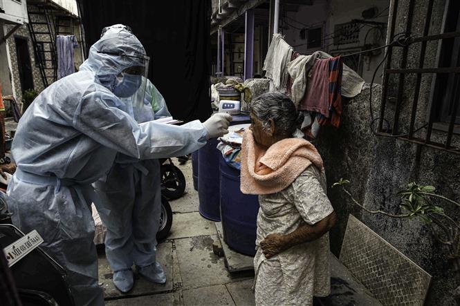 Kiểm tra thân nhiệt người dân sống trong một khu ổ chuột ở Mumabai, Ấn Độ. Ảnh: AFP/TTXVN