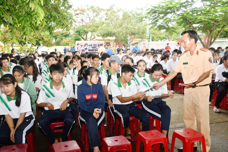 Phát tờ rơi tuyên truyền an toàn giao thông cho học sinh. Ảnh: T. Huyền