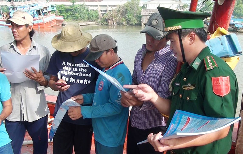 Cán bộ Trạm Kiểm soát biên phòng Bình Thắng (Bình Đại) phát tờ rơi tuyên truyền pháp luật cho các ngư dân. Ảnh: B.Cương