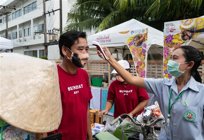 Kiểm tra thân nhiệt cho người dân để phòng lây nhiễm COVID-19 tại một hội chợ ẩm thực ở Phuket, Thái Lan. Ảnh: THX/ TTXVN