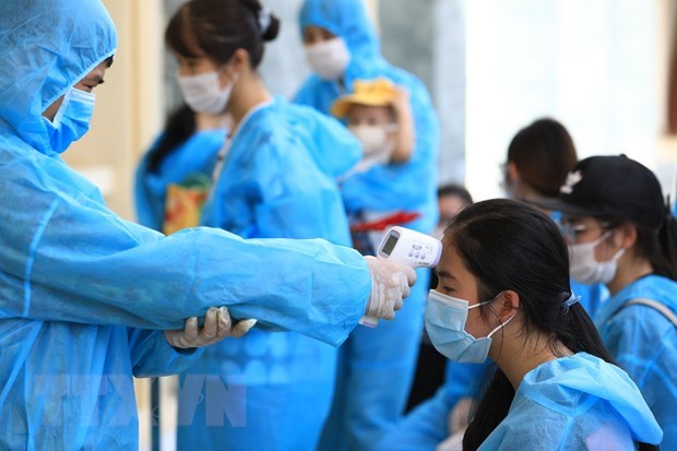 Phát hiện người nước ngoài mắc COVID-19 sau khi rời Việt Nam Nhân viên y tế đo thân nhiệt. Ảnh: TTXVN/Vietnam+