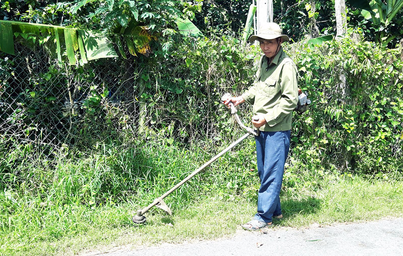 Ông Dương Văn Phính cắt cỏ làm đẹp đường phố.