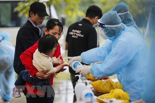 Các bác sĩ thực hiện sát khuẩn tay cho một cháu bé trong đoàn công dân cách ly tập trung theo dõi COVID-19 tại Trung đoàn 814, Bộ chỉ huy Quân sự tỉnh Hòa Bình. Ảnh minh họa: TTXVN