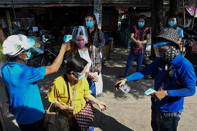 Thế giới trên 1,5 triệu người tử vong; Mỹ liên tiếp phá kỷ lục buồn Kiểm tra thân nhiệt cho hành khách trước khi lên xe buýt tại Manila, Philippines. Ảnh: AFP/TTXVN