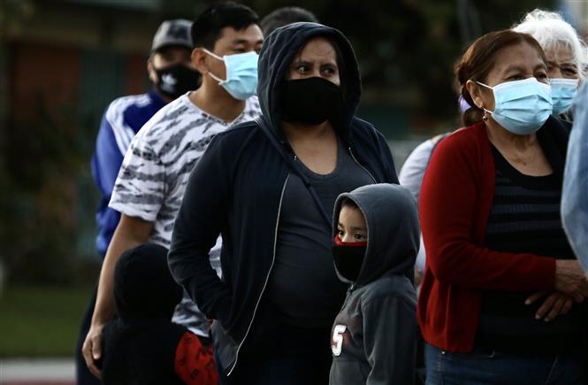 Người dân đeo khẩu trang phòng lây nhiễm COVID-19 khi xếp hàng chờ nhận hàng phân phát tại Los Angeles, California, Mỹ, ngày 19-11-2020. Ảnh: THX/TTXVN