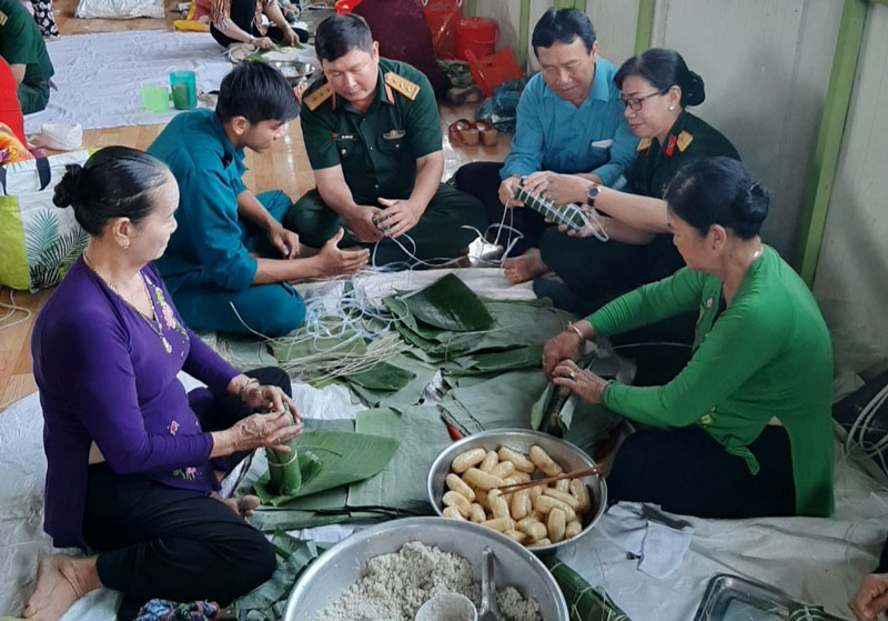 Cán bộ, chiến sĩ Ban Chỉ huy Quân sự huyện Chợ Lách cùng tham gia gói bánh tét với người dân. Ảnh: Văn Thiện