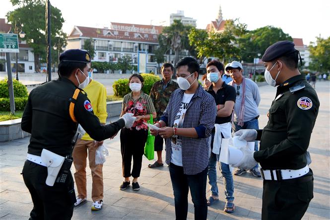 Cảnh sát phát khẩu trang miễn phí cho người dân để phòng lây nhiễm COVID-19 tại Phnom Penh, Campuchia. Ảnh: AFP/TTXVN