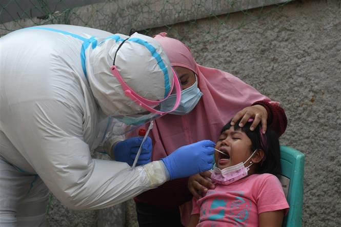 COVID-19 tới 6h sáng 24-5-2021: Ấn Độ vượt 300.000 người chết, nguy cơ làn sóng thứ ba Nhân viên y tế lấy mẫu xét nghiệm COVID-19 cho trẻ em tại Jakarta, Indonesia, ngày 20-5-2021. Ảnh: THX/ TTXVN