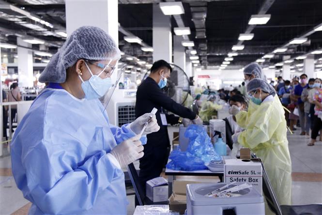 Mỹ chia sẻ 55 triệu liều vaccine cho các nước; Ấn Độ lập kỷ lục tiêm vaccine mỗi ngày Một nhân viên y tế chuẩn bị vaccine trước khi tiêm cho người dân tại 1 điểm tiêm ở thủ đô Vientiane. Ảnh: Phạm Kiên - Phóng viên TTXVN tại Lào