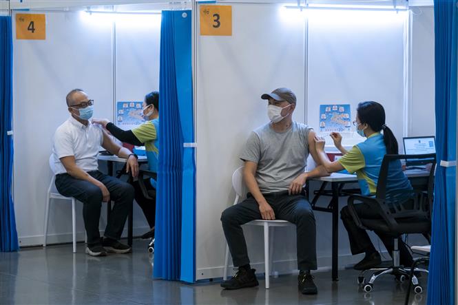 Mỹ ghi nhận gần 100.000 ca mắc mới; WHO khuyến cáo dừng tiêm mũi vaccine thứ 3 Nhân viên y tế tiêm chủng vaccine ngừa COVID-19 cho người dân tại Hong Kong, Trung Quốc. Ảnh: AFP/TXVN