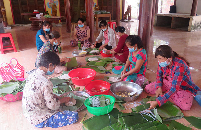 Phụ nữ Tân Ngãi miệt mài, chăm chút gói từng đòn bánh tét.