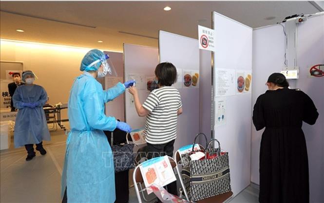 Nhân viên y tế lấy mẫu xét nghiệm COVID-19 của hành khách tại sân bay Narita, Nhật Bản. Ảnh: Asahi Shimbun/TTXVN