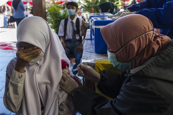 Nhân viên y tế tiêm chủng vaccine ngừa COVID-19 cho học sinh tại Surabaya, Indonesia, ngày 1-9-2021. Ảnh: AFP/TTXVN