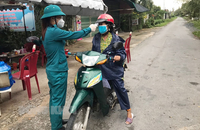 Nữ Phó chỉ huy trưởng Quân sự năng nổ, nhiệt tình Chị Nguyễn Thị Ngọc Diệu đo thân nhiệt cho người dân tại chốt kiểm dịch Covid-19. Ảnh: Đặng Thạch