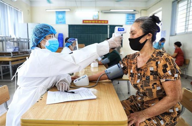 Tối 9-9-2021, thêm 12.420 ca mắc COVID-19 và 12.523 người khỏi bệnh Nhân viên y tế kiểm tra nhiệt độ và huyết áp cho người dân trước khi tiêm vaccine phòng COVID-19. Ảnh: Thành Đạt/TTXVN