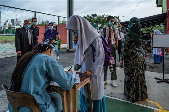 Kiểm tra thân nhiệt nhằm ngăn chặn sự lây lan của dịch COVID-19 tại một trường học ở Kuala Lumpur, Malaysia. Ảnh: AFP/TTXVN