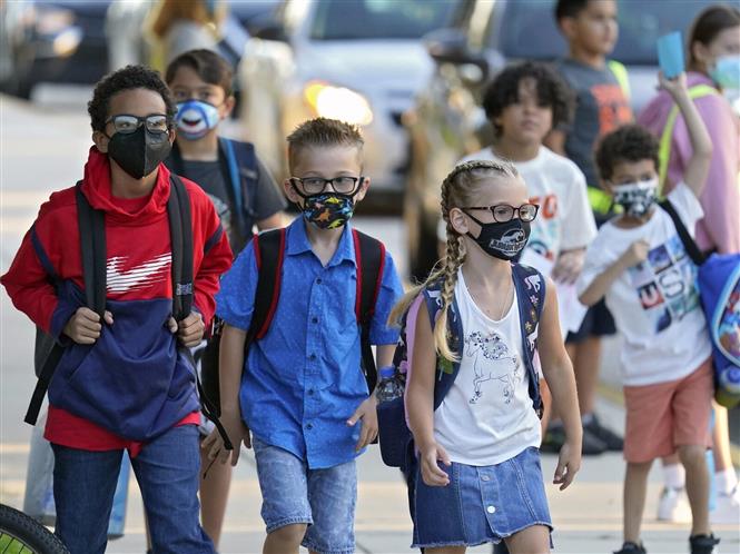 Các em nhỏ đeo khẩu trang phòng dịch COVID-19 khi ngày đầu tiên trở lại trường học sau thời gian dài giãn cách, tại Riverview, bang Florida (Mỹ) ngày 10-8-2021. Ảnh: AP/TTXVN