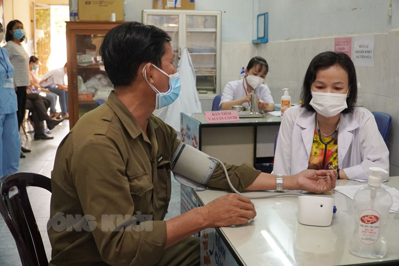 Cán bộ y tế khám sàng lọc trước khi tiêm vắc-xin phòng Covid-19.