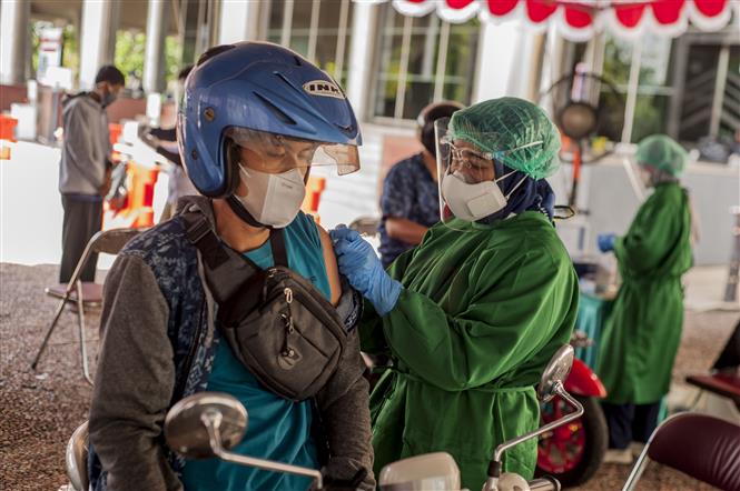 Thêm 6.860 người chết, Mỹ tăng gấp đôi ca tử vong mới Nhân viên y tế tiêm vaccine ngừa COVID-19 cho người dân tại Yogyakarta, Indonesia. Ảnh: THX/TTXVN