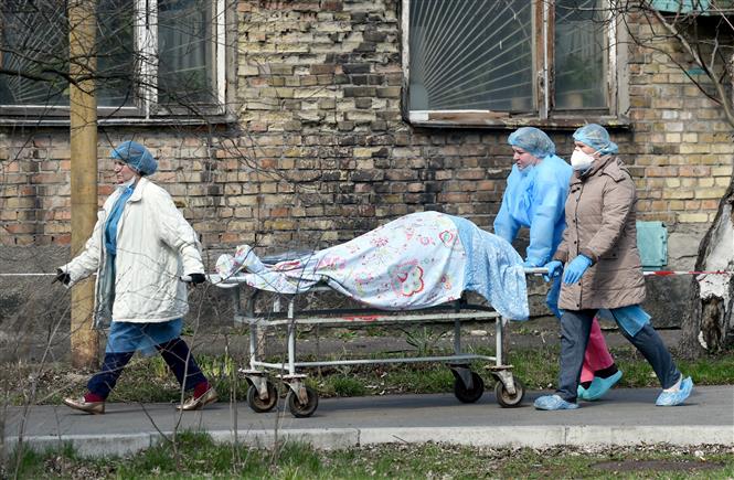 Nhân viên y tế chuyển bệnh nhân tử vong do COVID-19 tới nhà xác bệnh viện ở Kiev, Ukraine. Ảnh: AFP/TTXVN