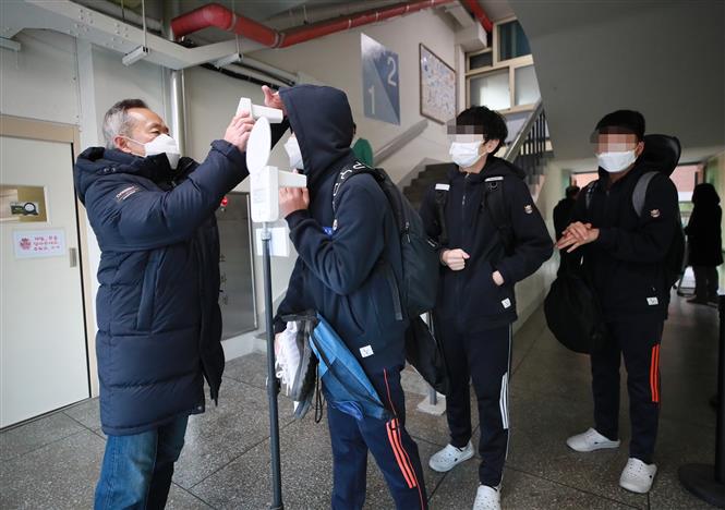 Kiểm tra thân nhiệt nhằm ngăn chặn sự lây lan của dịch COVID-19 tại một trường học ở Seoul, Hàn Quốc, ngày 22-11-2021. Ảnh: YONHAP/TTXVN