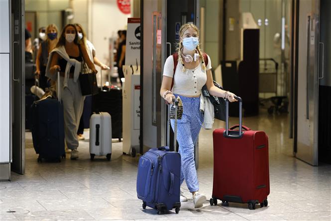 Hành khách đeo khẩu trang phòng lây nhiễm COVID-19 tại sân bay Heathrow, London, Anh, ngày 2-8-2021. Ảnh: AFP/TTXVN