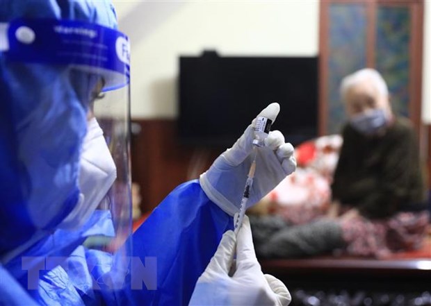 Y tá Hoàng Thùy Linh (trạm y tế phường Hàng Bài, Hoàn Kiếm) chuẩn bị tiêm vaccine Pfizer cho người cao tuổi, có bệnh lý nền ngay tại nhà. Ảnh: Hoàng Hiếu/TTXVN