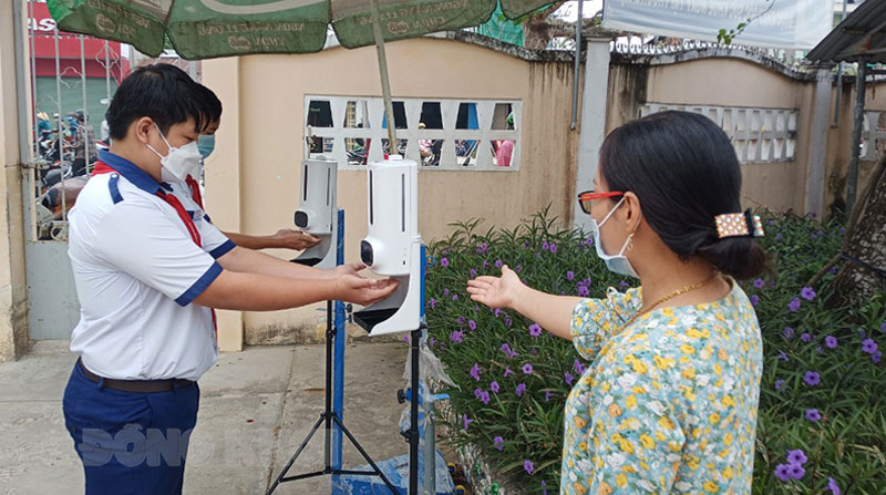 Học sinh Trường THCS thị trấn Giồng Trôm khử khuẩn trước khi vào cổng trường.