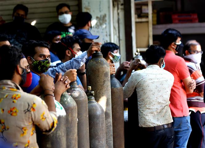 Người dân xếp hàng chờ bơm đầy bình oxy để cung cấp cho bệnh nhân COVID-19 tại New Delhi, Ấn Độ. Ảnh: THX/ TTXVN